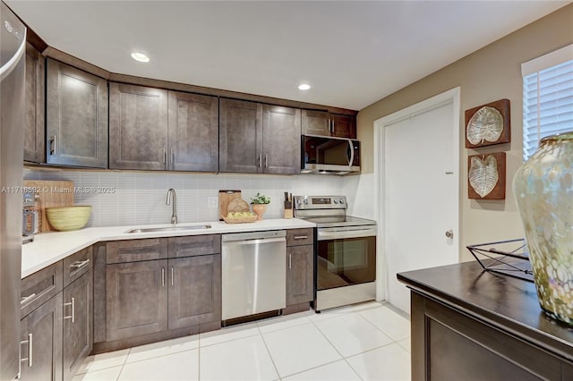 kitchen with sink, light tile patterned floors, appliances with stainless steel finishes, tasteful backsplash, and dark brown cabinetry