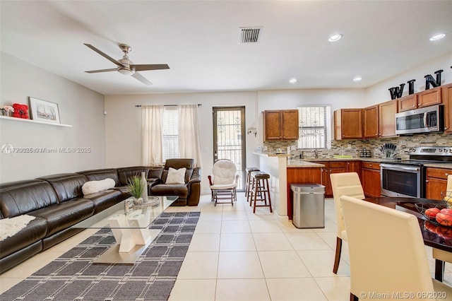 living room featuring ceiling fan, sink, and light tile patterned floors