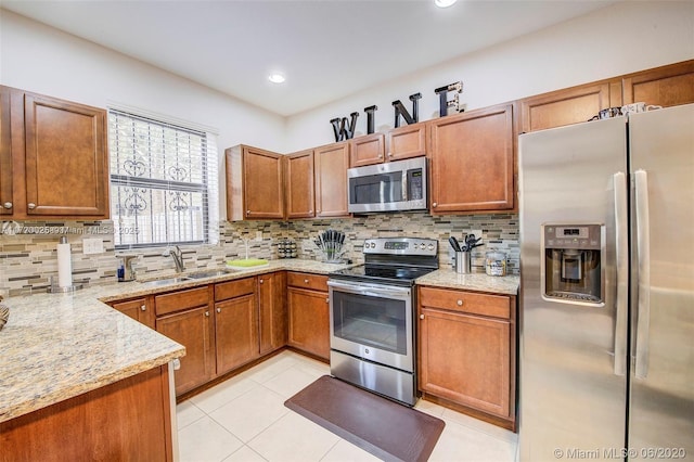 kitchen featuring sink, tasteful backsplash, light stone counters, light tile patterned floors, and appliances with stainless steel finishes