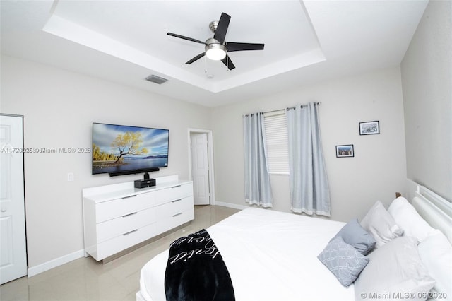 bedroom with ceiling fan and a raised ceiling