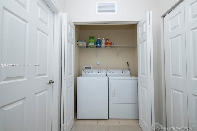 laundry room with separate washer and dryer and light tile patterned flooring