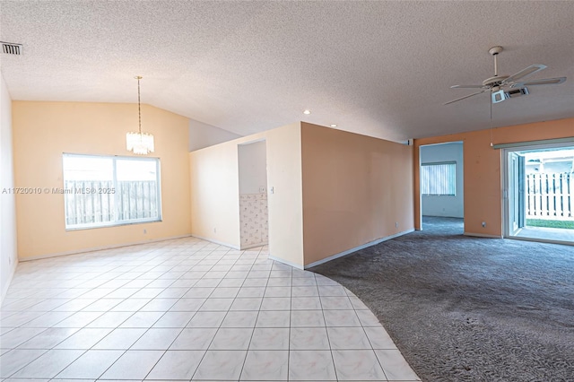 tiled empty room featuring a textured ceiling, ceiling fan with notable chandelier, and lofted ceiling