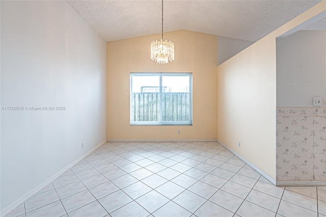 empty room with light tile patterned flooring, lofted ceiling, a textured ceiling, and an inviting chandelier