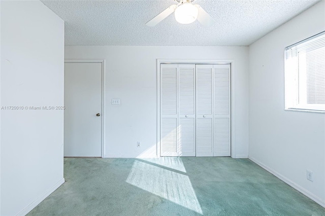 unfurnished bedroom featuring a textured ceiling, a closet, light colored carpet, and ceiling fan