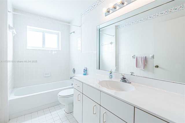 full bathroom with vanity, tile patterned floors, tiled shower / bath combo, toilet, and tile walls