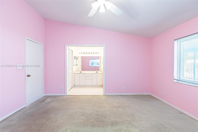 spare room with sink, ceiling fan, light colored carpet, and a textured ceiling