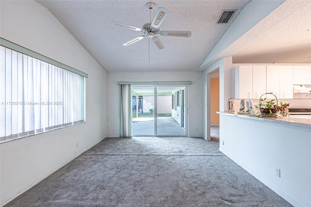 unfurnished living room with carpet, a textured ceiling, vaulted ceiling, and ceiling fan