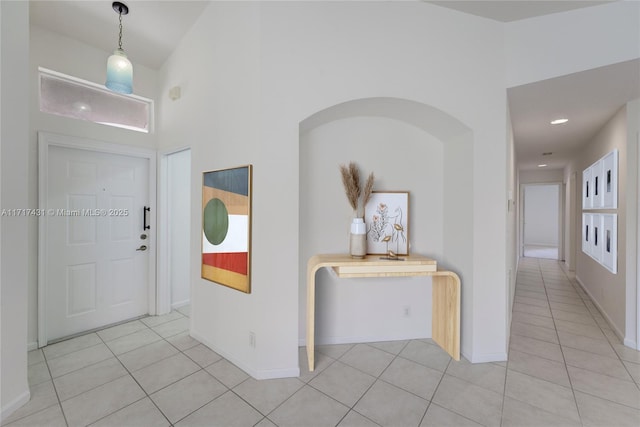 foyer with a high ceiling, light tile patterned flooring, and baseboards