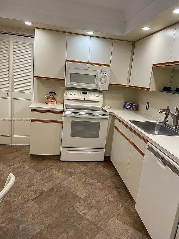 kitchen featuring white appliances, white cabinetry, and sink