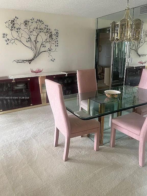 dining space featuring a chandelier, a textured ceiling, and carpet floors