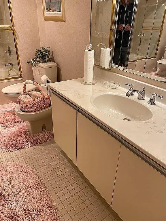 full bathroom featuring toilet, vanity, tile patterned floors, and combined bath / shower with glass door