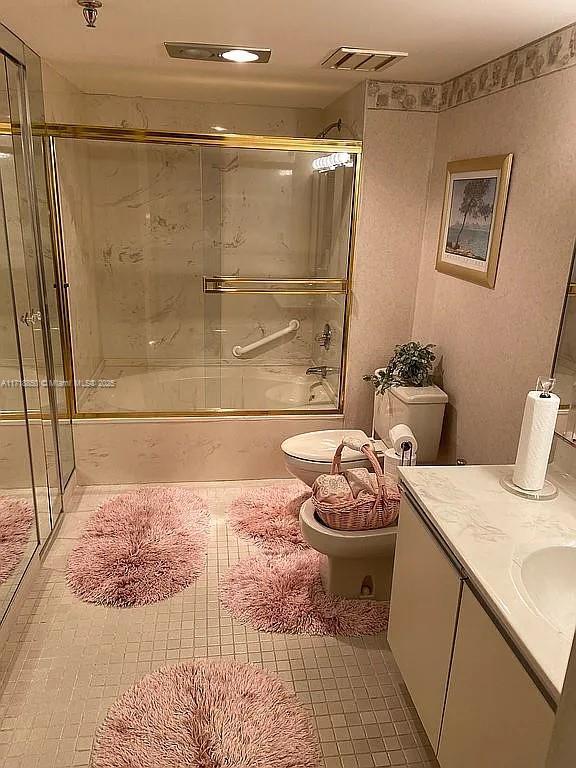 full bathroom with combined bath / shower with glass door, toilet, and vanity