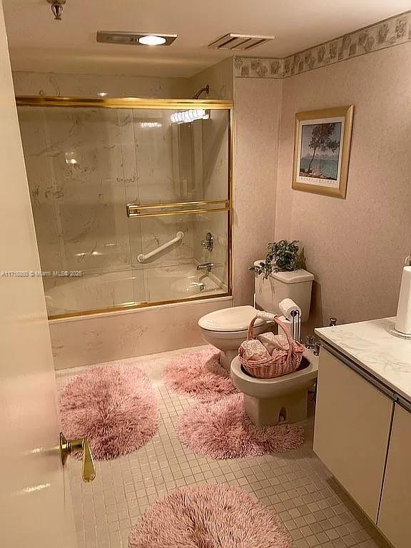 full bathroom featuring combined bath / shower with glass door, tile patterned floors, a bidet, toilet, and vanity