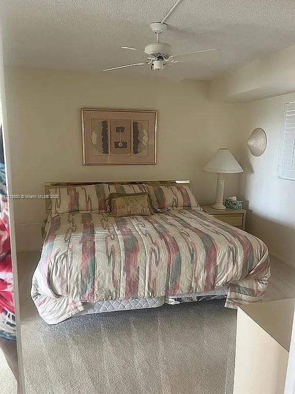 carpeted bedroom featuring a textured ceiling and ceiling fan