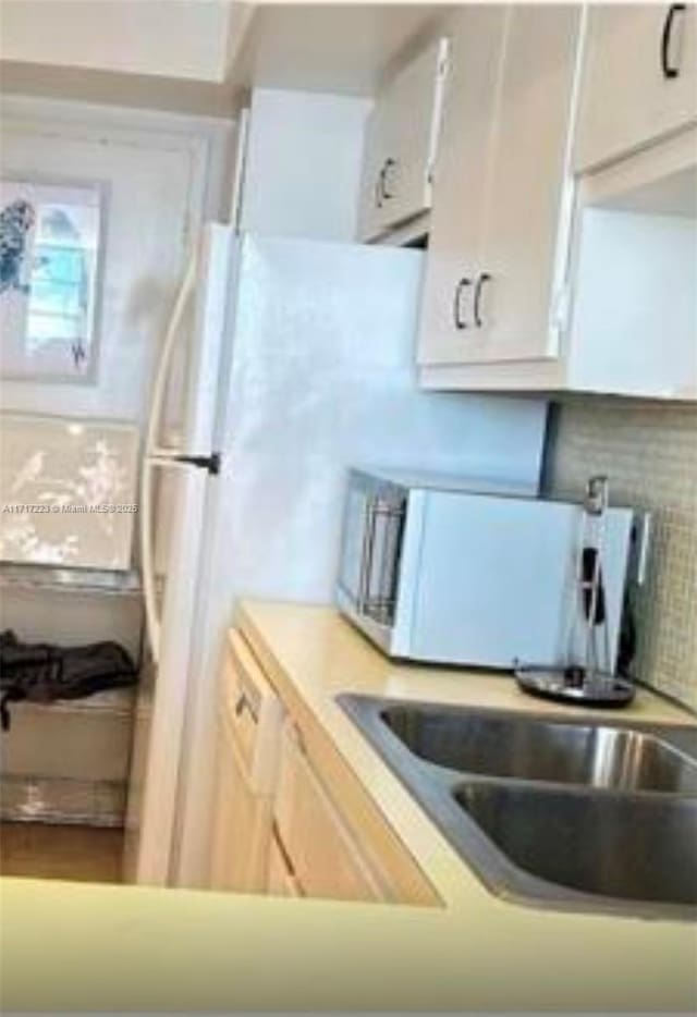 kitchen with decorative backsplash, sink, white cabinets, and white dishwasher