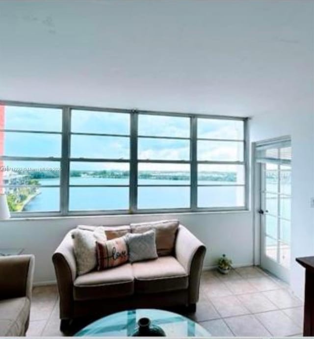 living room featuring light tile patterned floors, a water view, and french doors