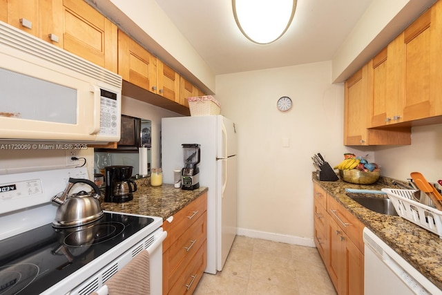 kitchen with sink, light tile patterned flooring, dark stone counters, and white appliances