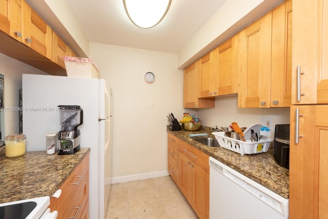 kitchen with white appliances, dark stone counters, and sink