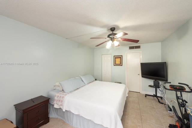 bedroom featuring ceiling fan, light tile patterned floors, a textured ceiling, and a closet