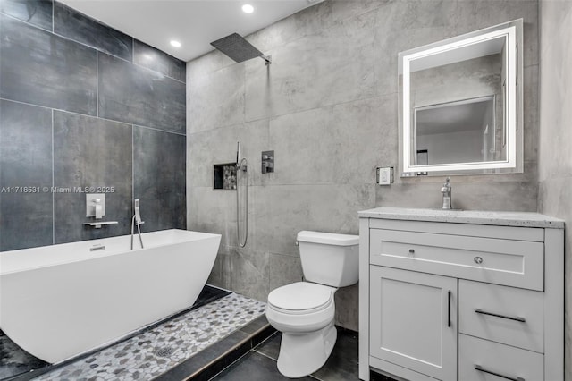 full bathroom with tile patterned floors, vanity, tile walls, shower with separate bathtub, and toilet