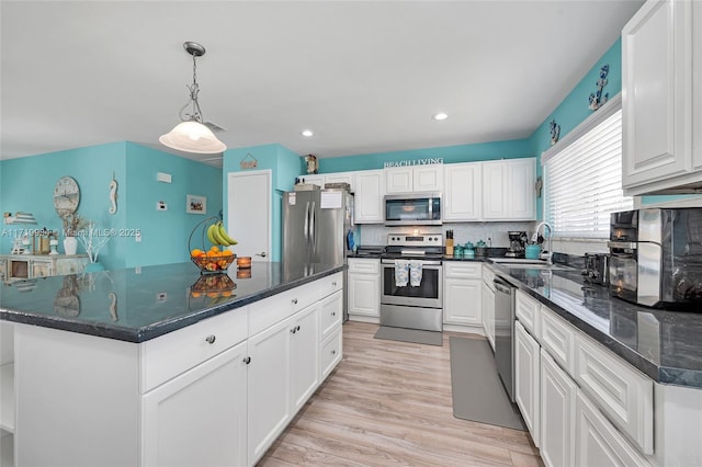 kitchen with a center island, white cabinets, sink, hanging light fixtures, and stainless steel appliances