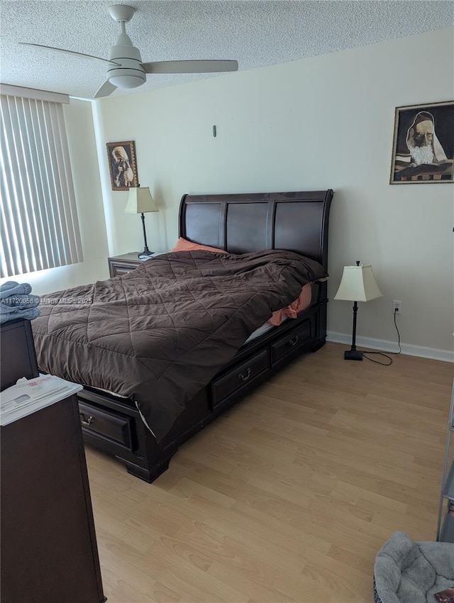 bedroom with ceiling fan, light hardwood / wood-style flooring, and a textured ceiling