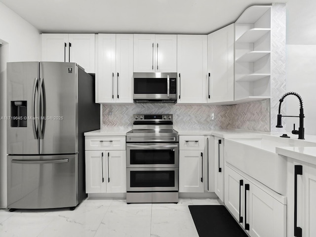 kitchen featuring decorative backsplash, white cabinetry, sink, and appliances with stainless steel finishes