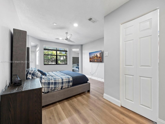 bedroom with ceiling fan, light hardwood / wood-style floors, and a closet