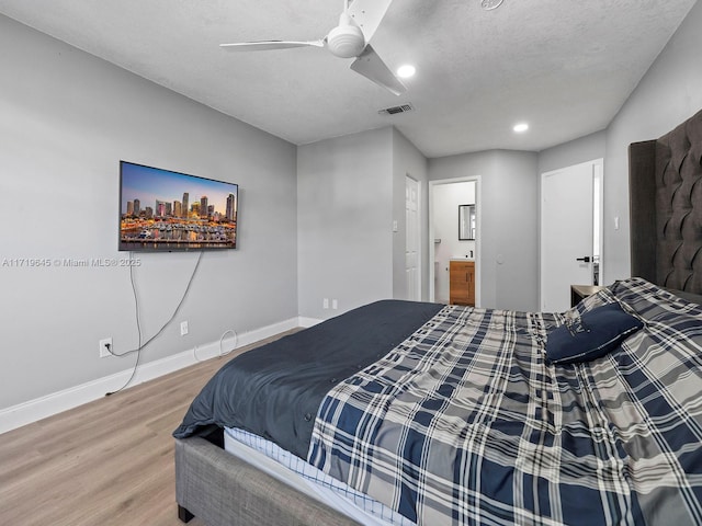 bedroom featuring hardwood / wood-style floors, ceiling fan, a textured ceiling, and ensuite bath