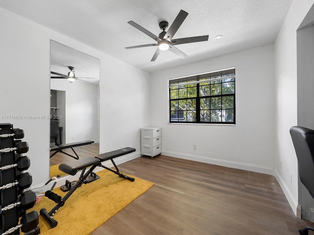 exercise room with ceiling fan, a textured ceiling, and hardwood / wood-style flooring