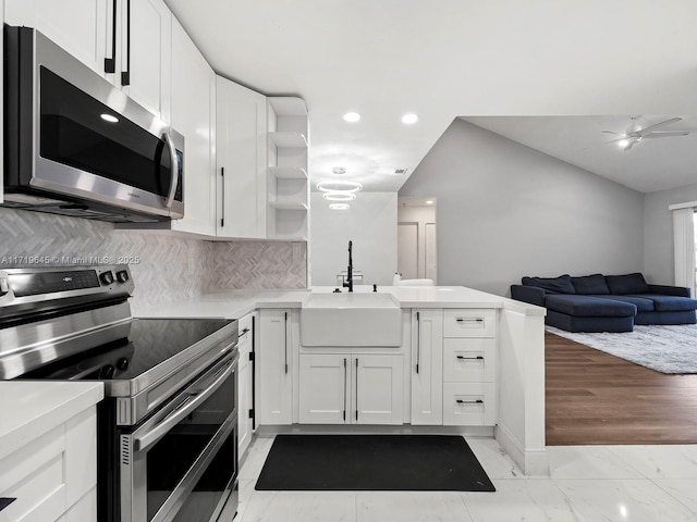 kitchen featuring white cabinets, kitchen peninsula, sink, and appliances with stainless steel finishes