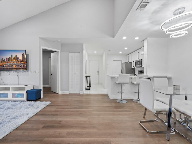 interior space with a chandelier, vaulted ceiling, and light wood-type flooring