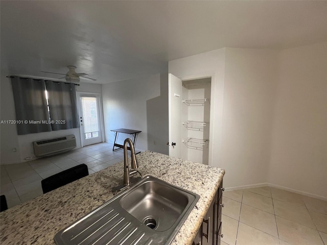 kitchen featuring light stone counters, sink, light tile patterned floors, and a wall unit AC