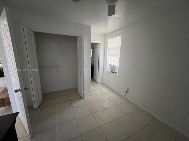 unfurnished bedroom with a closet, light tile patterned flooring, cooling unit, and ceiling fan