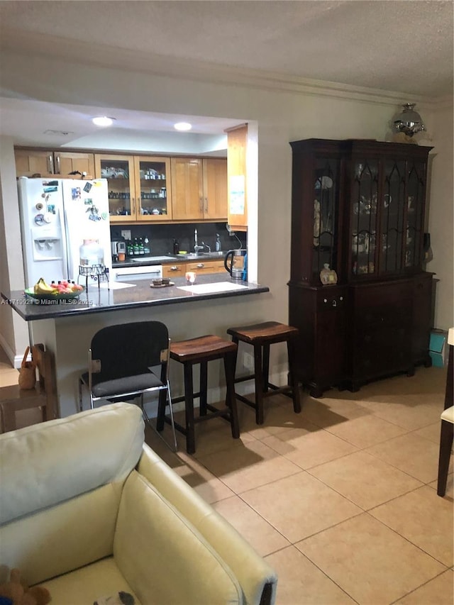 kitchen featuring white refrigerator with ice dispenser, crown molding, light tile patterned floors, tasteful backsplash, and kitchen peninsula