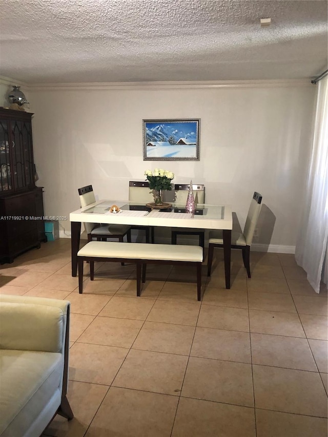 tiled dining space with a textured ceiling and ornamental molding