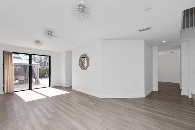 empty room with light hardwood / wood-style flooring and a notable chandelier