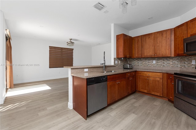 kitchen with sink, kitchen peninsula, stainless steel appliances, and light wood-type flooring