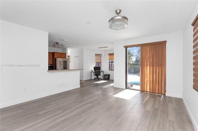 unfurnished living room featuring light wood-type flooring and an inviting chandelier