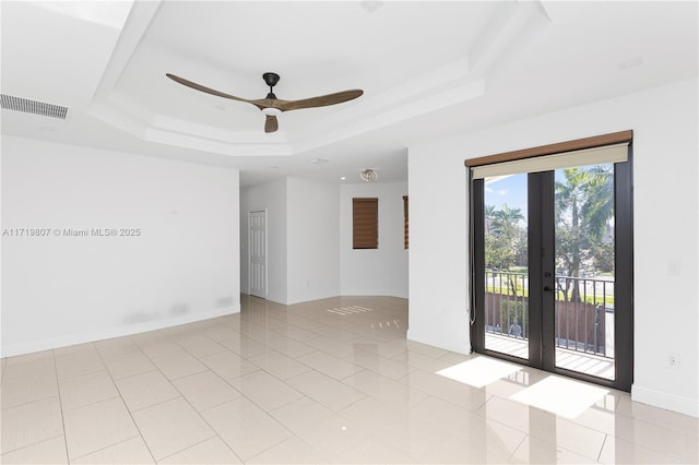 tiled spare room with ceiling fan, a raised ceiling, and french doors