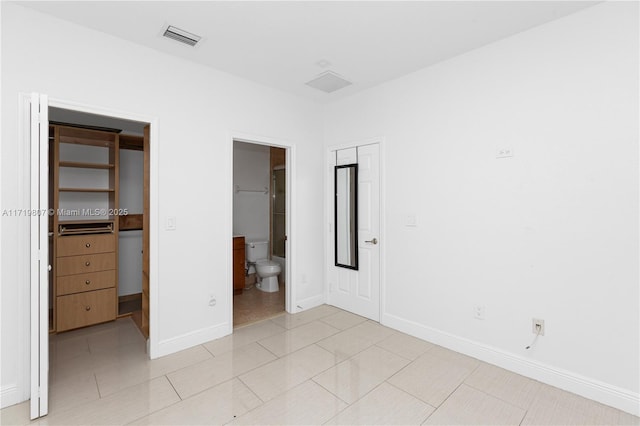 unfurnished bedroom featuring light tile patterned flooring and connected bathroom