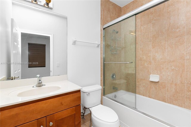 full bathroom featuring vanity, enclosed tub / shower combo, and toilet