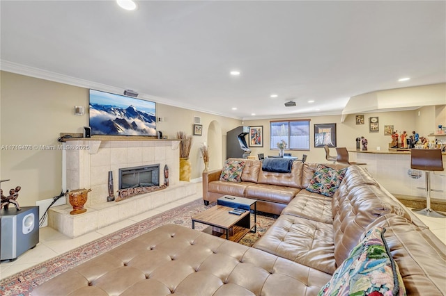 living room featuring a tiled fireplace, crown molding, and light tile patterned floors