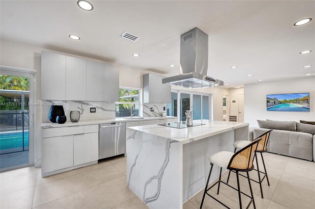 kitchen with stainless steel dishwasher, a center island, island range hood, and white cabinetry