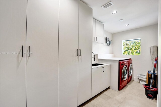 clothes washing area featuring cabinets, washing machine and dryer, and sink