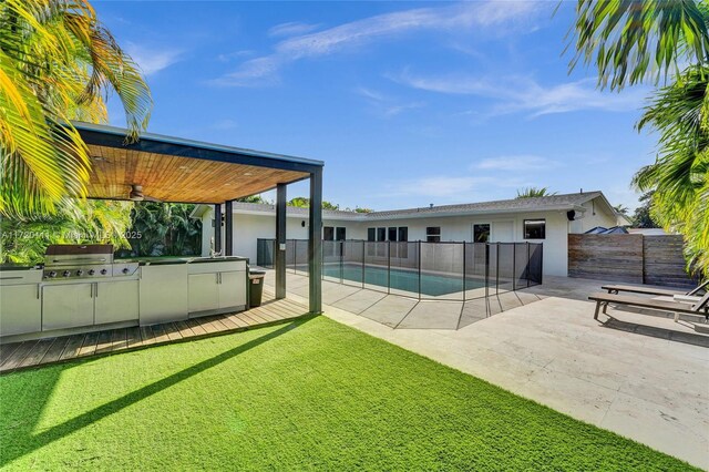 view of swimming pool with area for grilling, a grill, ceiling fan, a patio area, and a lawn