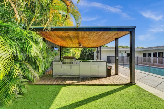 exterior space featuring a swimming pool side deck, ceiling fan, and an outdoor kitchen