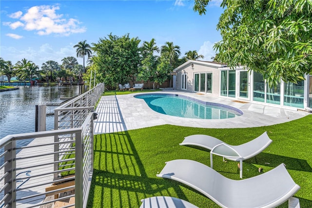 view of pool with a water view, a yard, a patio, and a dock