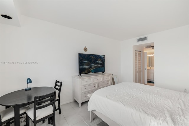 bedroom with ensuite bath and light tile patterned flooring