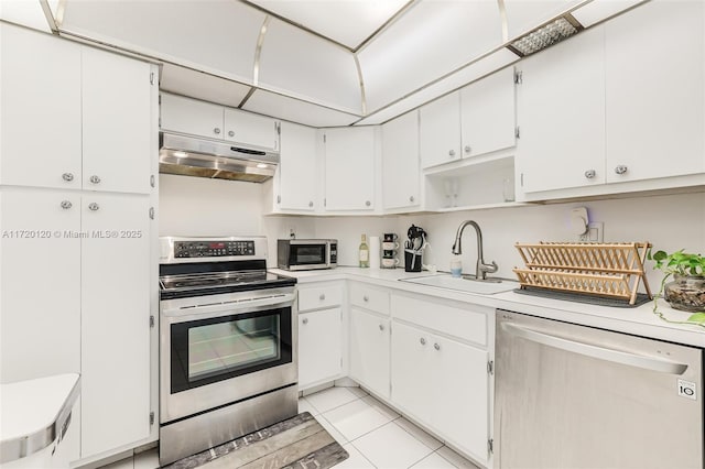 kitchen featuring white cabinets, appliances with stainless steel finishes, light tile patterned flooring, and sink